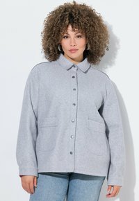 Grijze fleece jas met een kraag, drukknoopsluiting en twee voorzakken. Zachte textuur met een relaxte pasvorm en rechte snit.