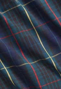 Tartan tyg i marinblått och mörkblått, med röda och guld linjer. Mjuk textur, med ett harmoniskt, symmetriskt rutmönster.