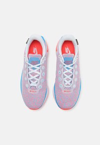 Nike copati z mrežastim zgornjim delom, v roza, modri in beli barvni shemi, okrogli odprtini za vezalke ter živahnimi rdečimi vložki. Vključeno je GORE-TEX označevanje.
