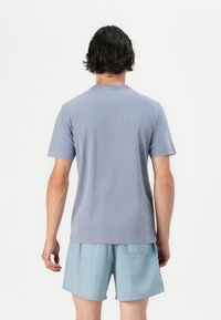 Lyseblå bomulds T-shirt med korte ærmer, rund halsudskæring og en glat tekstur, vist fra ryggen med lyseblå shorts.