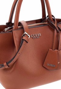 Borsa a tracolla in pelle marrone con texture, con doppi manici e tracolla rimovibile, hardware in argento. Caratterizzata da logo e dettagli della marca.