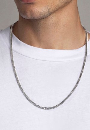 Silberne Metallkette mit einem glatten, runden Glieddesign, die auf dem Kragen eines weißen T-Shirts ruht, Nahaufnahme des Ausschnitts.