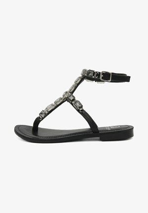 Černé sandály na plochém podpatku s texturovaným páskem, zdobené řadou průhledných, obdélníkových drahokamů a páskem s přezkou u kotníku.