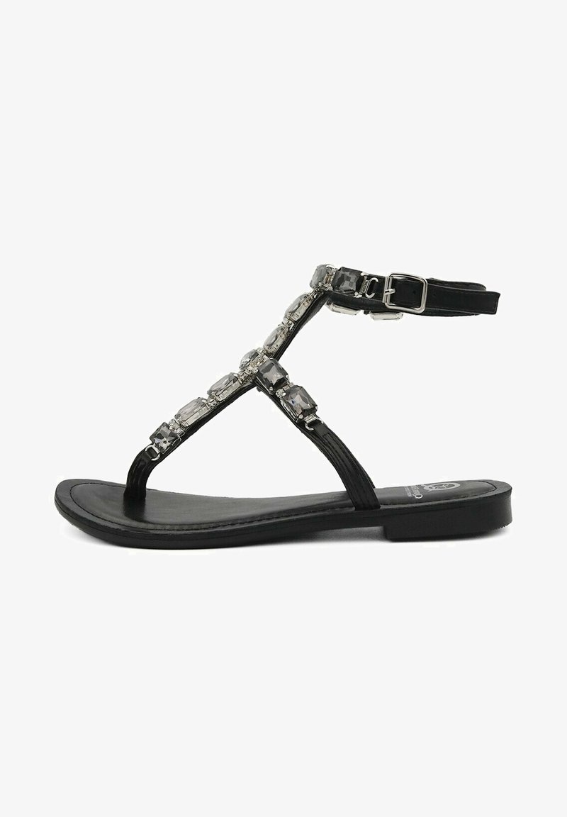 Sandalias planas negras con una correa texturizada, que cuentan con una fila decorativa de piedras preciosas transparentes y rectangulares y una correa de hebilla en el tobillo.