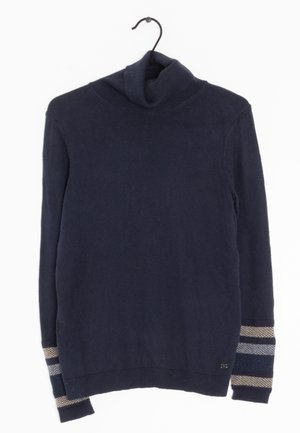 Navy blue turtleneck sweater with long sleeves and beige, gray, and blue stripes near the cuffs, hanging on a black hanger.