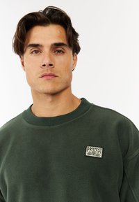 Groene fleece sweatshirt met een gestructureerde afwerking, met een ronde hals en een klein 'PROTEST' logo op de linkerborst.