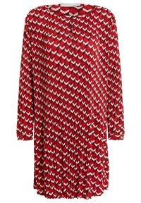 Robe rouge à manches longues, avec un motif géométrique blanc. Le tissu est plissé et elle a un col rond avec un détail de bouton.