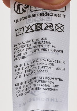 Vaatemerkissä hoito-ohjeet: pesu 40°C, ei valkaisua, ei rumpukuivausta, ei silittämistä, ei kemiallista pesua; kangas 83 % polyesteriä, 17 % elastaania.