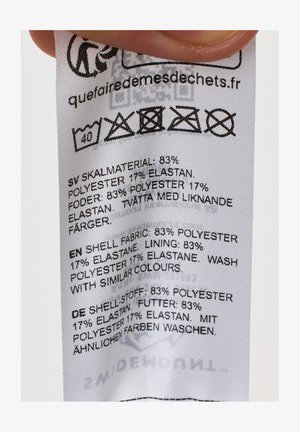 Vaatemerkissä hoito-ohjeet: pesu 40°C, ei valkaisua, ei rumpukuivausta, ei silittämistä, ei kemiallista pesua; kangas 83 % polyesteriä, 17 % elastaania.