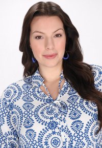 Bluză albă cu model floral albastru, având un guler cu șnur și detalii subtile cu nasturi. Mâneci lungi și largi, dintr-un material texturat și fin.
