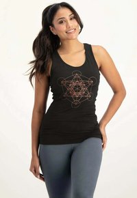 Schwarzes Tanktop mit geometrischem Design in Kupfer. Der Stoff ist glatt und hat einen körperbetonten Schnitt. Kombiniert mit grauen Leggings.