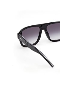 Černé sluneční brýle s lesklým povrchem, šedými gradientovými skly, obdélníkovým rámem a štíhlými stranami s logem na jedné straně.