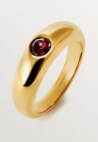 Anillo de oro con un diseño suave y redondeado, que presenta una piedra preciosa de color rojo profundo engastada en un bisel pulido. Apariencia simple y elegante.