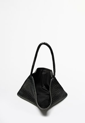 Czarna pleciona torba na ramię o trójkątnym kształcie, teksturowanej powierzchni, plecionych uchwytach oraz przestronnym wnętrzu wyłożonym czarną tkaniną.