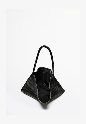 Zwarte geweven draagtas met een driehoekige vorm, een textuurrijk oppervlak, gevlochten handvatten en een ruime binnenkant bekleed met zwarte stof.
