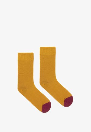 Żółte bawełniane skarpetki z prążkowanym mankietem, z bordowymi palcami. Gładka tekstura, długość do połowy łydki i prosty design.