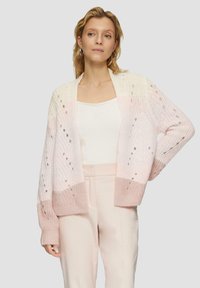 Sweter kardigan z otwartym przodem, o gradacji od kremowego do jasnoróżowego, z teksturowanym wzorem i szczegółami w postaci wycięć.