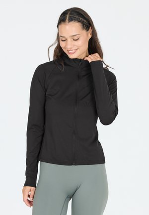 Black zip-up jacket with a high collar and long sleeves, made from a smooth, stretchy material, paired with light green leggings.