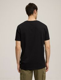 Czarny bawełniany t-shirt z krótkim rękawem, luźny krój, okrągły dekolt i gładki design. Widok z tyłu pokazuje gładką strukturę i staranne wykończenie.