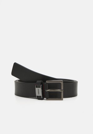 Schwarzer Ledergürtel mit einer glänzenden silbernen Schnalle und schwarzem Kontraststich. Der Gürtel ist flach und glatt und weist ein klassisches Design auf.