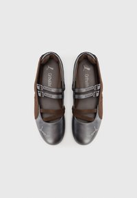 Chaussures marron et grises à finition lisse, avec des sangles élastiques croisées et des doubles boucles. Comprend le logo Puma sur le bout.