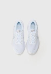 White mesh sneakers with light blue accents, featuring a textured design, round toe, and flat laces. Nike logo on the side and tongue.