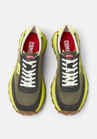 Gröna och grå sneakers har en kraftig gul sula, vita snören och en röd logotyp på tungan. Räfflad gummisula för bra grepp.