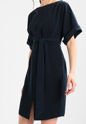 Vestido navy en un tejido suave con mangas cortas enrolladas, una cintura entallada con un cinturón atado y un corte a la altura de la rodilla con una abertura lateral.