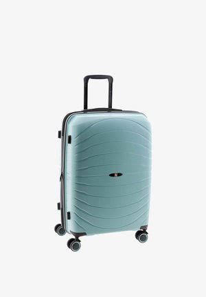 Valise rigide bleu clair avec texture ondulée, quatre roues pivotantes et poignée télescopique noire étendue.