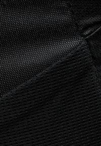 Svart textil med ett strukturerat mönster med kontrasterande vävningar, som visar en jämn yta och en profilerad form.