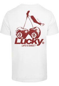 Fehér póló, amelyen piros grafika látható két cseresznyéről, mindkettőn a szám 8-mal, alatta pedig a "Lucky LIFE'S SWEET" felirattal.