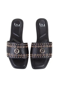 Sandali neri slip-on con una fascia ampia, dotati di borchie in tono oro e un dettaglio del logo esagonale. La suola è piatta e liscia.