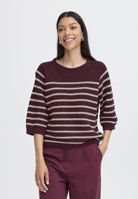 Maroon and beige striped sweater with a ribbed texture, round neck, and three-quarter sleeves, paired with plum trousers.