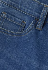 Tela de mezclilla en azul medio con un bolsillo visible, costuras doradas en contraste y una textura suave, con un lazo para cinturón estándar.