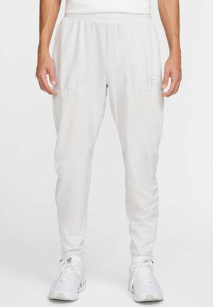 Pantalons de sport légers et blancs avec taille élastique, deux poches latérales et un logo discret sur la poche gauche ; texture lisse.