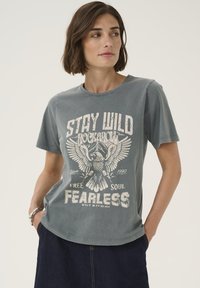 Graues kurzärmeliges T-Shirt mit Rundhalsausschnitt, versehen mit einem Adlermotiv und dem Text „STAY WILD ROCKBROW“ in kontrastierendem weißen Druck.