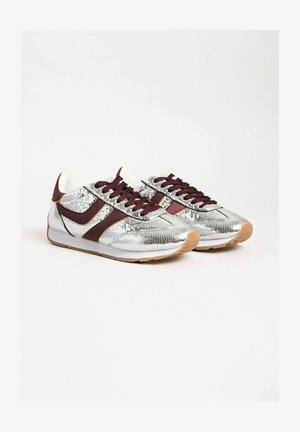 Fémes ezüst sportcipők bordó részletekkel, texturált felülettel, fehér béléssel és gumitalppal. Tartósságért felelős barna talp.