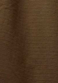 Tissu marron avec un motif en grille texturé présentant de petites formes rectangulaires tissées et de légers plis.