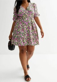 Blumenkleid mit kurzen Puffärmeln, das rosa, lila und grüne Blumen auf schwarzem Hintergrund zeigt. Es beinhaltet einen Bindegürtel und einen ausgestellten Rock.