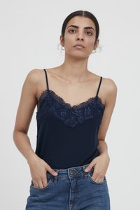 Camiseta navy con encaje en el escote y tirantes finos, fabricada en una tela suave, combinada con pantalones cortos de mezclilla.