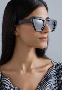 Black oversized sunglasses with angular frames and mirrored lenses. Smooth texture; no visible patterns or hardware details.
