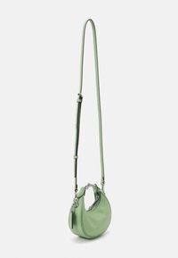 Petit sac bandoulière en cuir vert clair en forme de croissant avec une longue bandoulière réglable et des ferrures argentées.