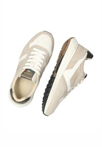Zapatillas de ante gris claro y crema con una entresuela blanca y suela negra. Presentan un diseño de cordones y acentos en dorado en la lengüeta.