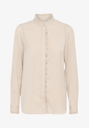 Blouse beige à manches longues en tissu lisse, avec un plastron et un col volantés, fermeture à boutons et manches à poignet.