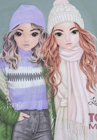 Illustration von zwei Mädchen in Winteroutfits. Eines trägt einen lila Pullover und eine grüne Jacke, das andere einen weißen Schal und eine Mütze.