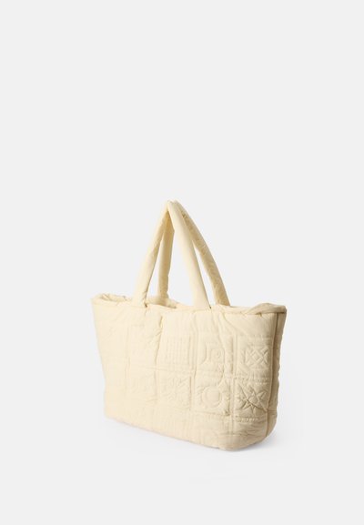 Borsa tote trapuntata di colore crema, caratterizzata da quadrati testurizzati con motivi variati. Tessuto morbido e imbottito e due robusti manici arrotondati.