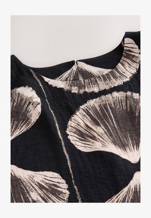 Fekete szövetfelső nagy, bézs absztrakt kagylómintákkal. A nyakkivágás kerek, apró hátul hasítékkal díszítve.