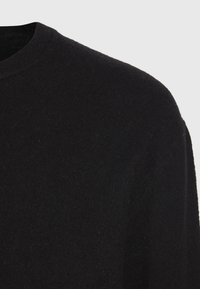 Schwarzer Strickpullover mit rundem Halsausschnitt. Der Stoff wirkt weich mit einer feinen Textur und minimaler Detailgestaltung und bietet ein glattes Finish.