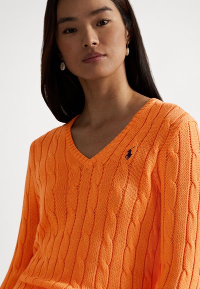 Camisola com gola em V e padrão de malha com tranças, em laranja brilhante, apresentando um padrão texturizado e um pequeno destaque de logótipo no lado esquerdo. Tecido macio.