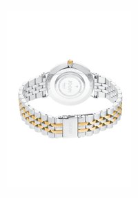 Silberne und goldfarbene Armbanduhr mit einem Armband aus Edelstahl, rundem Gehäuse und einer gekrönten Lünette. Verfügt über einen transparenten Rücken mit Branding.